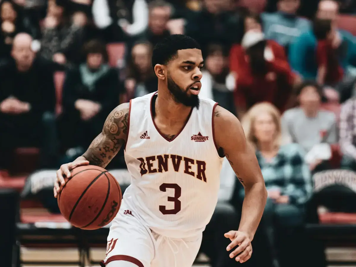 College basketball guard driving to the basket in front of a crowd