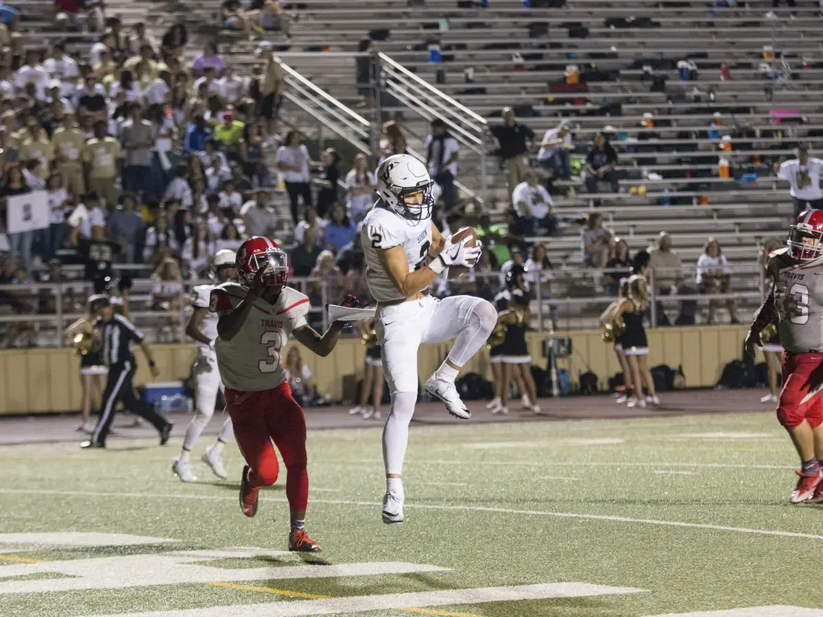 Wide receiver making a catch in front of a packed high school stadium