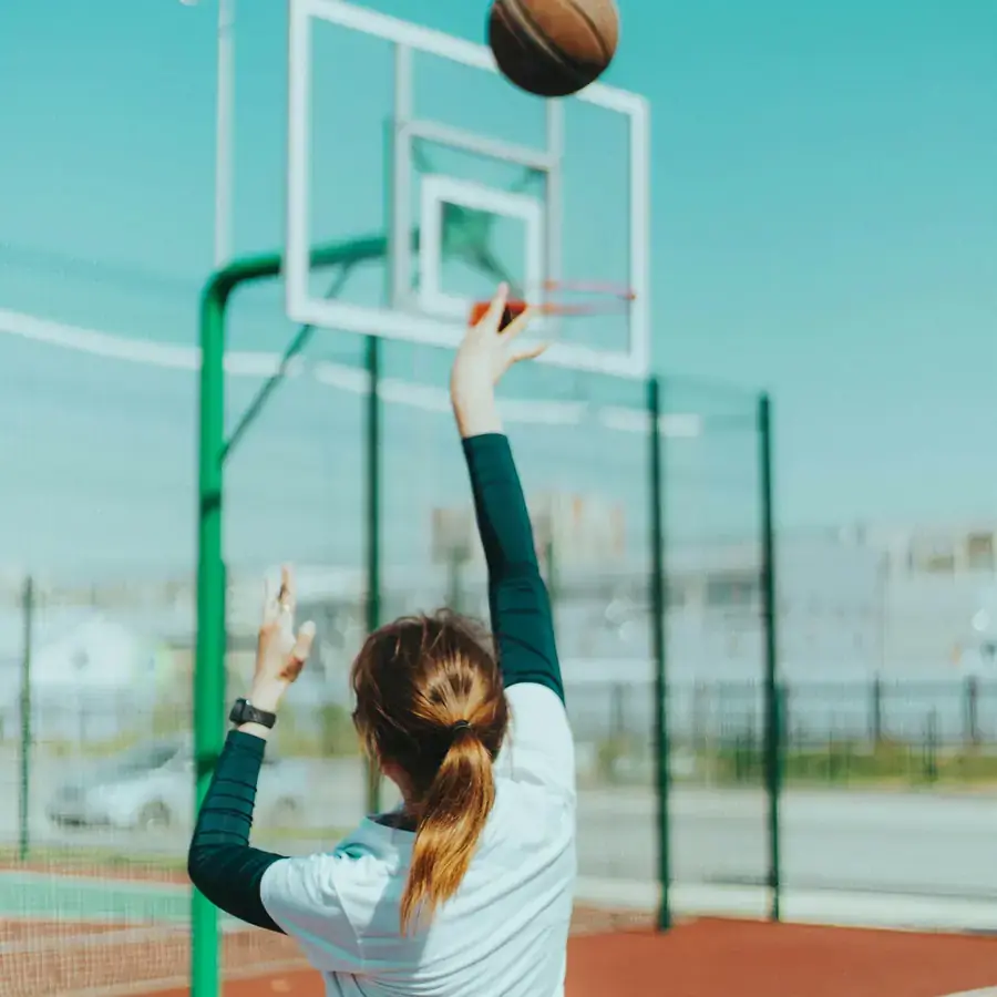 Basketball player shooting on an outdoor court under a clear sky