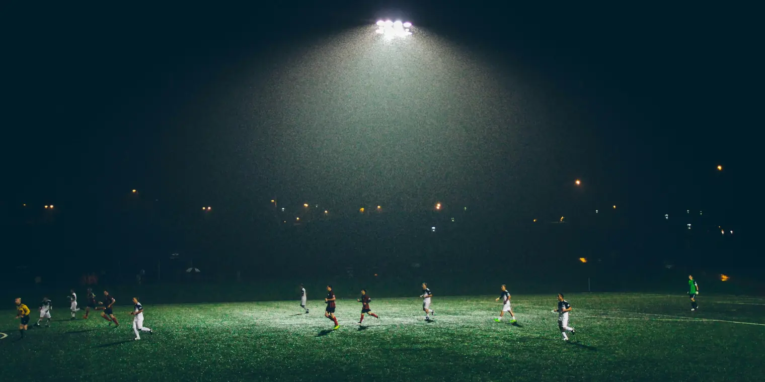 Soccer players competing under stadium lights during a night game